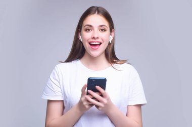 Young woman using phone device gadget app isolated over studio background. Girl holding a smartphone, chatting by mobile phone. Girl using phone, studio portrait. Woman makes telephone call on phone