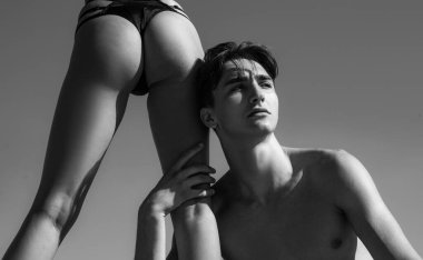 Yakışıklı erkek arkadaşının yanında duran bikinili seksi seksi seksi kadın. Seksi arzu ve aşk konsepti. Güzel genç aşıklar berrak mavi bir arka planda izole edilmiş