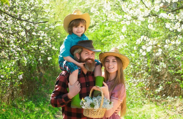 Cheerful family on picnic in a park. Family Farmers working in tree garden at spring. Father mother and child work in yard with gardener tools