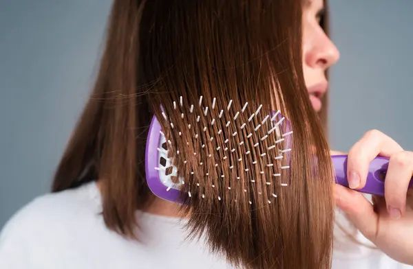 Close up woman brushing hair with comb. Beautiful girl with long hair hairbrush