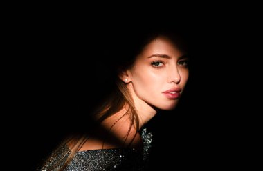 Stüdyoda poz veren genç bir kadın. Işık ve gölge. Yüzünde koyu renk ışık olan güzel bir kadının moda portresi. Kızların yüzü gölgeli, çekici kadın model.