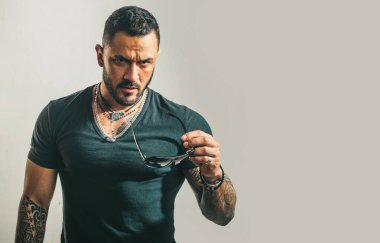 Güneş gözlüklü yakışıklı, kendine güvenen bir adam. Stüdyoda poz veren ciddi biri. Erkekler cinsellik, cazibe ve karizma