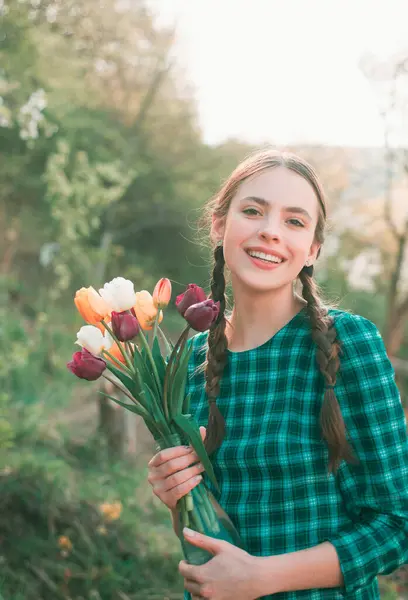 Happy beauty girl holding tulips in the garden