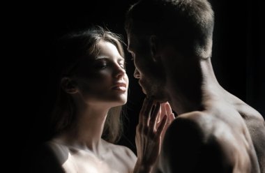 Birbirine aşık romantik bir çift siyah arka planda sarılıp öpüşüyor. Şehvetli çift öpücüğü. Ben de seni seviyorum. Romantik ve aşk