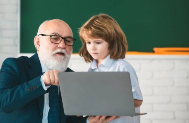 Okula dönelim. Bilgisayarlı öğretmen ve çocuk. Çevrimiçi eğitim ve öğrenme kavramı. Öğrenci çocuk sınıfında. Yaşlı öğretmen ve genç öğrenci.