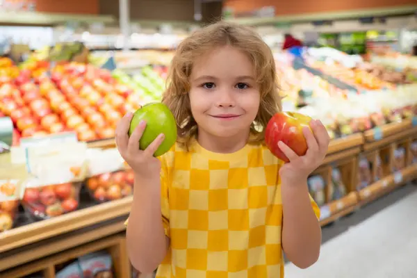 子供は食料品店でリンゴフルーツを持っています スーパーで果物を買う子供たち 小さな男の子は食料品店で新鮮な野菜を買っています 野菜を選択する子供 健康的な食べ物 — ストック写真