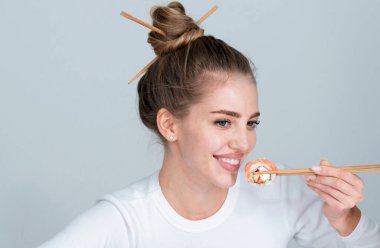 Suşi yiyen seksi bir kadının portresi. Suşi rulo, sashimi. Manken kız yemek çubuklarıyla suşi yiyor. Yemek çubuklarıyla saç kesimi, sağlıklı Japon yemekleri yemek.