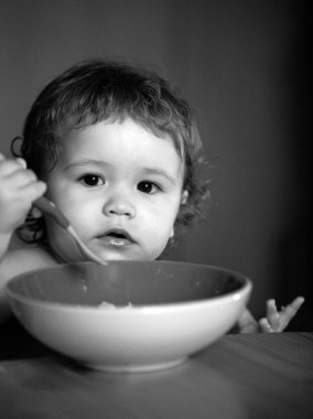 Bebek mutfakta bulaşık ve kaşıkla çorba içiyor.