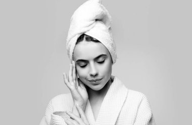 Şehvetli bir kız yüzüne nemlendirici krem sürüyor. Kusursuz ciltli genç bir kızın fotoğrafı. Cilt bakımı ve güzellik kavramı