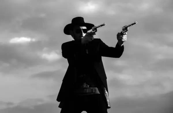 Cowboy shooting. Sheriff officer in black suit and cowboy hat. Man with wild west guns, vintage pistol revolver and marshal ammunition. US Marshals, American western Sheriff. Wild west with cowboy