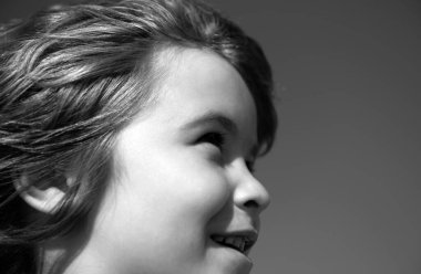 Küçük çocuğun portresi mavi gökyüzüne fotokopi aletiyle bakıyor. Kafa vuruşu çocuk portresi