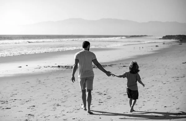 Father and son walking on summer beach