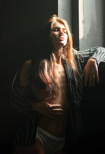 Sexy alluring woman, sensual young model looking seduce on black studio. Fashion portrait of elegant woman in shadow, glamor light. Sensual seductive girl