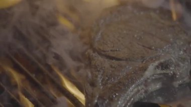 Kızarmış et ve ateş. Yemek ve yemek. Yanan ızgaranın üstünde et pişiyor. Izgara et. Kızarmış mermer biftek ateşte. Izgarada alevli biftek var. Barbekü ve ızgara. Kızarmış et.