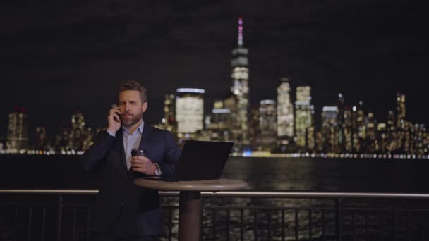 在纽约市 商人在户外用笔记本电脑在智能手机上聊天 在纽约外工作的成熟商人 夜店交易 夜生活 纽约的商人 — 图库视频影像