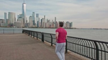 Son sınıf öğrencisi yolda koşuyor. Formda erkek fitness koşucusu ve NYC arka planında koşucu. Manhattan nehir kenarında koşan olgun bir adam. Olgun sporcu parkta koşuyor.