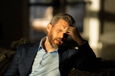 Yorgun adamın korkunç bir baş ağrısı var. Bitkin, sağlıksız hisseden, baş ağrısı hastalığına üzülen bir adam. Stresli orta yaşlı bir adamın baş ağrısı olan portresi. Migren ve baş ağrısı konsepti