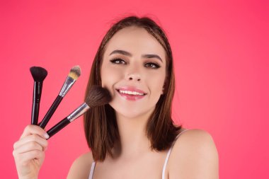 Beauty girl with makeup brushes. Make up for woman. Girl with makeup brushes near face. Cosmetic brush. Facial Makeup. Female model applying blush powder foundation tone