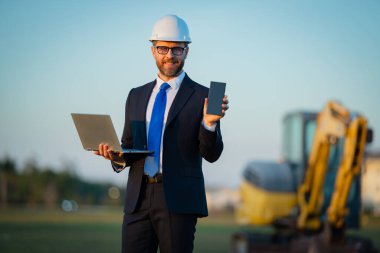 Mühendis, inşaat müdürü ya da bir inşaatta yönetici. Takım elbiseli ve kasklı bir yönetici. Yatırımcı, inşaat müdürü. Geliştirici, açık hava portresi. Orta yaşlı mimar