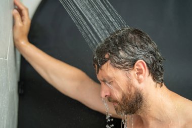 Orta yaşlı bir adam banyoda saç yıkıyor. Küvette banyo yapan adam. Yüzü duşta köpüklü. Banyo yapan adam duş alıyor. Duş alan adamı kapatın. Duş konsepti. İnsan duşta su altındadır.