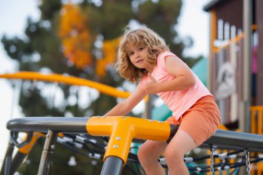 Portrait of child doing rock climbing with background playground