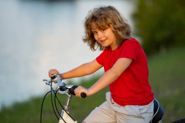Bisiklete binen çocuk. Şehir parkında bisiklet süren bir çocuk. Önce çocuk bisikleti. Çocuk yaz etkinliklerinde. Bisikletli çocuk. Yaz parkında bisiklet süren küçük bir çocuk.