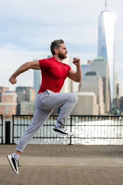 逃げる ニューヨーク市で走る健康な男 フィットネススポーツ 男ランナーはマンハッタンの近くでジョギングしています アメリカン ストリートで走る男 スポーツ服でニューヨークで走る男 成熟したランナーのためのスポーツウェア — ストック写真