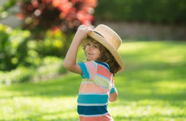 Yaz parkındaki sevimli bir çocuğun portresi. Hasır şapkalı beyaz çocuğu kapatın. Komik çocuk. Yaz tatili