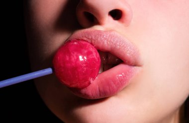 Seksi ağzı olan, chupa yiyen bir kız. Kadın dudakları lolipop emiyor. Oral seks konsepti. Ağzında lolipop tutan kadın, kapat. Kırmızı dudaklar, şehvetli ve seks dükkanı konsepti