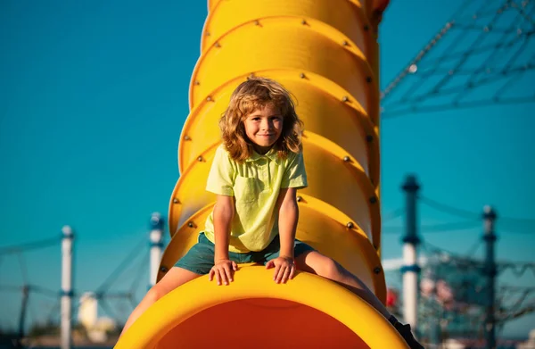 Child on slide playground area. Summer leisure for kids