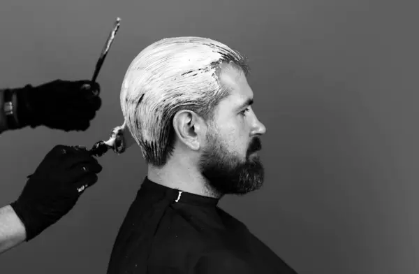 Bearded man color hair. Process of a man hair coloring at hairdresser salon