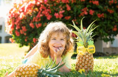 Elinde ananas tutan çocuk fotokopi alanı ile yaz arkaplanı pozu veriyor. Çocuklar için sağlıklı meyve kavramı