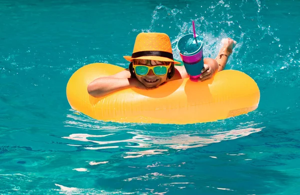 Child in swim pool swimming on inflatable ring. Kid swim with orange float. Water toy, healthy outdoor sport activity for children. Kids beach fun. Fashion summer kids hat