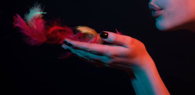 Seksi dudaklar. Seksi tombul dudaklı kadın melek tüyü üflüyor. Dudak bakımı ve güzellik