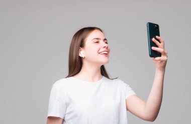 Kız selfie çekiyor. İzole edilmiş gri arka planı olan genç bir kadın.