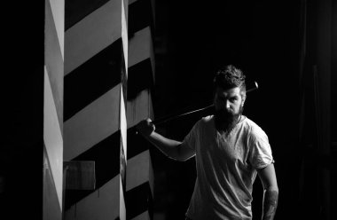 Ciddi yüzlü, kendine güveni tam çekici bir adam elinde beyzbol sopası tutuyor.