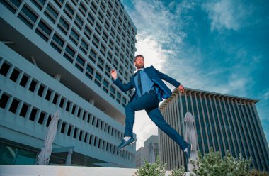 İşadamı koşuyor, işe gitmek için acele ediyor. Sokaklarda zıplarken tam boy genç iş adamı.