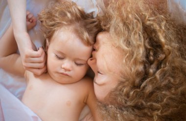 Anne ve bebek yatakta uyuyor. Yatak odasında aile sabahı. Günaydın.