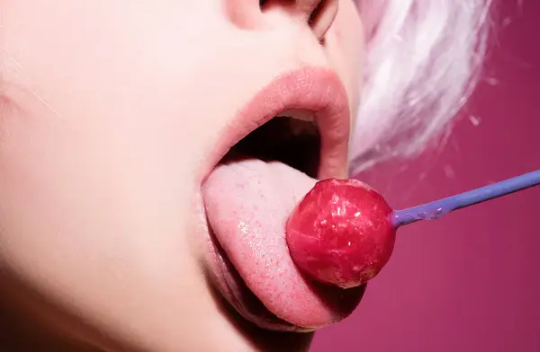 Licking candy. Lollipop model. Woman lips sucking a candy. Glamor sensual model with red lips eat sweats lolly pop