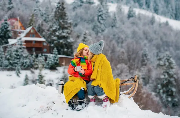 幸せな男の子と女の子は冬に眠っていた 冬には雪のスライドに乗っている子供たち 息子と娘はそりに乗るのを楽しむ — ストック写真