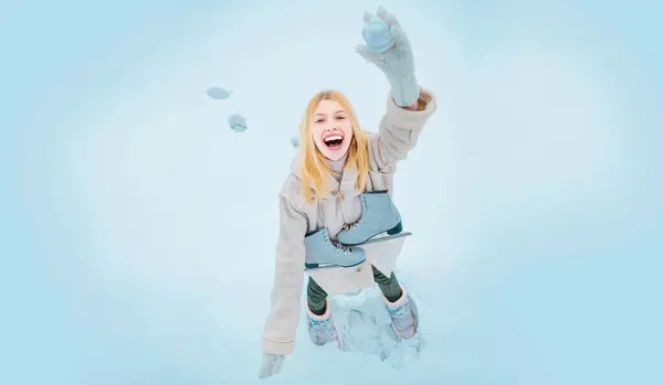 Girl throws snowballs. Snow games. Funny winter girl play with snow. Happy amazed girl in the snow make snowball. Winter activities in cold winter weather. Young girl laughing in snowy park