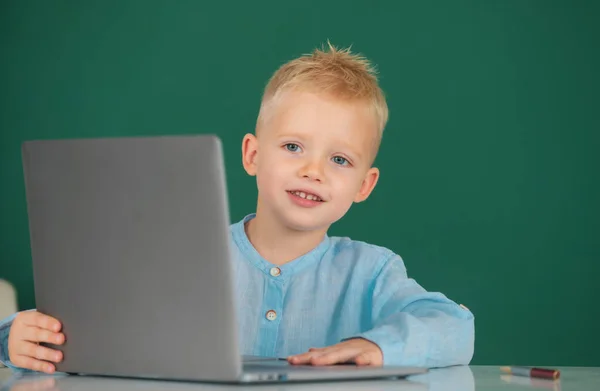 学校のノートパソコンを使っている子供 可愛いです生徒顔クローズアップ上の黒板の背景 — ストック写真