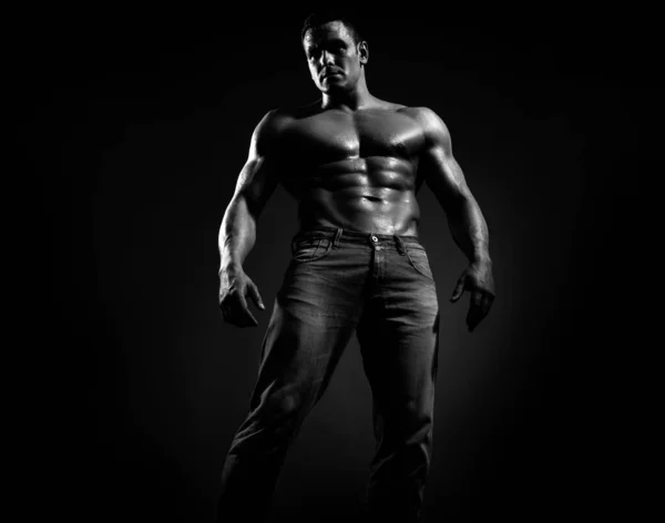 穿着牛仔裤的性感英俊的晒黑了的高加索男人 赤身裸体地站着 露出六块腹部 身材完美 黑黑的背景 — 图库照片