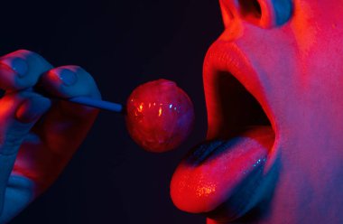 Pembe dudakları olan, lolipop tutan seksi bir kadın ağzı, güzellik kapanışı. Seksi kız lolipopu yaladı. Güzellik konsepti, yakın plan.