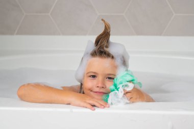 Sabun köpüklü banyo küveti. Çocuk köpük banyosu yapıyor. Banyo köpüğüyle banyo yapan küçük çocuk.