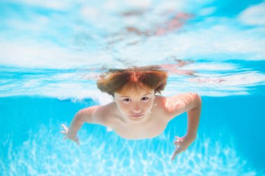 Kid boy swimming underwater on the beach on sea in summer. Blue ocean water. Child boy swimming in sea