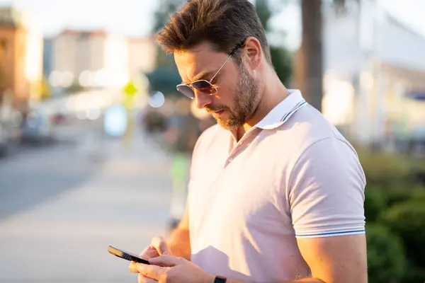 Man chatting on phone on the street. Handsome confident man talking on phone outside. Business phone conversation. Fashion man using phone in the street background in American city