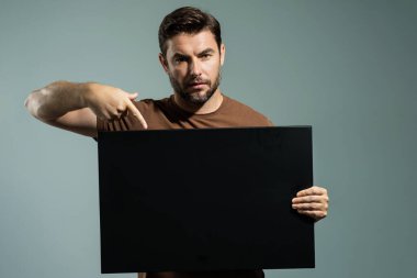 Adamın elinde fotokopi alanı var. Kopya uzay ürünü için pankart hazır. Kopyalama uzayı metnini imzala. Stüdyonun arka planında boş işaret panosu gösteren bir adam var. Boş kopya alanı boş tahtası