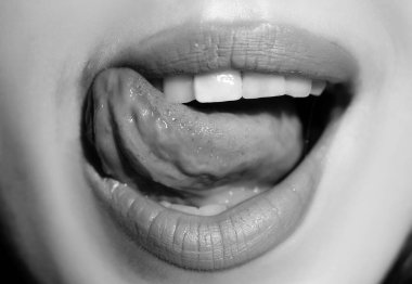 Seksi dudaklar, yakın çekim. Dilini yalayan şehvetli bir ağız. Baştan çıkarıcı dudak makyajı