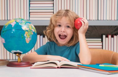 Kütüphanede kitapları ve elması olan okul çocuğu. İnek öğrenci. İlkokuldan zeki bir çocuk. Zeki dahi zeki çocuk öğrenmeye hazır.